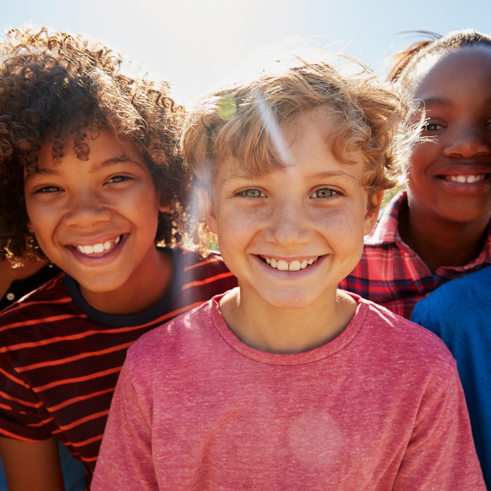 Close up of pre-teen friends in a park smiling to camera