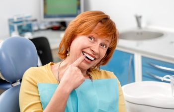 Smiling senior woman with new dental implants sitting in the dental office
