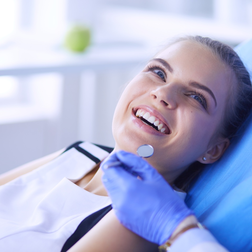 Young Female patient with pretty smile examining dental inspection at dentist office.