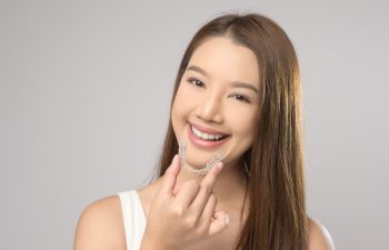A Young smiling woman holding invisalign braces over white background studio, dental healthcare and Orthodontic concept.